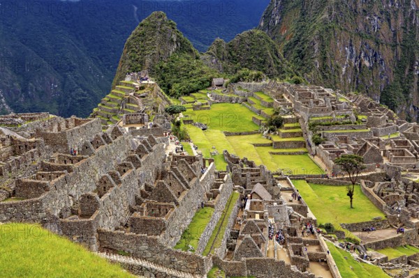 Extensive ruins and terraces in an ancient city nestled in mountains, the ruins of the Inca city of Machu Picchu in Peru
