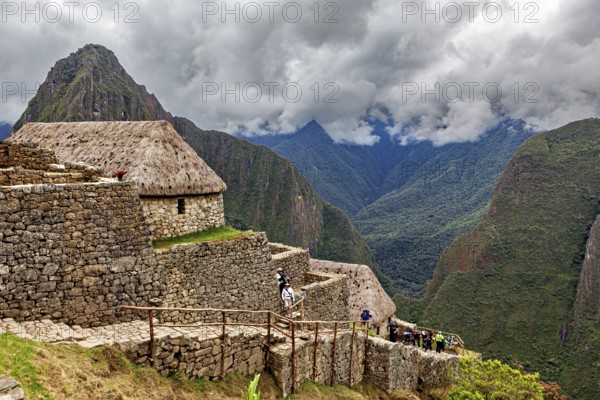 Historic ruins with grass-covered huts in the Andes against a cloudy sky, The ruins of the Inca city of Machu Picchu in Peru