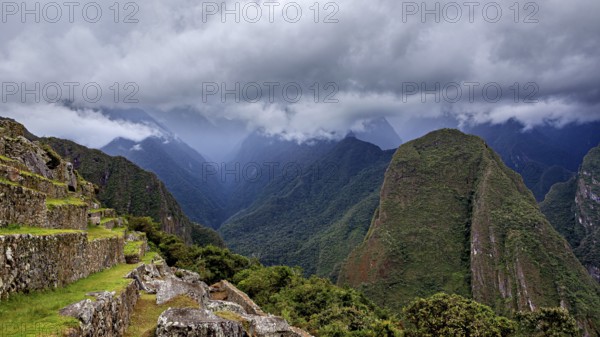 Dramatic mountain landscape with clouds and lush greenery interspersed with fog, The ruins of the Inca city of Machu Picchu in Peru