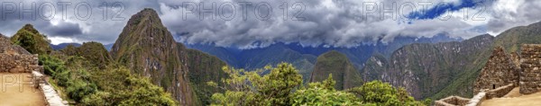 Panoramic view of dramatic mountains and wooded slopes under a cloudy sky near Machu Picchu, The ruins of the Inca city of Machu Picchu in Peru