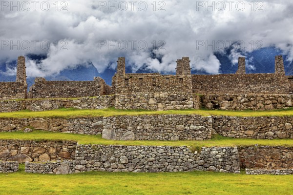 Stone ruins on several levels with mountains and clouds in the background, The ruins of the Inca city of Machu Picchu in Peru