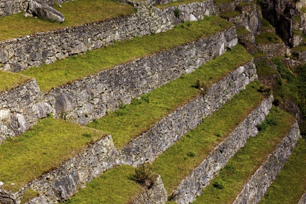 Close-up of hard stone terraces with grassy steps, The ruins of the Inca city of Machu Picchu in Peru