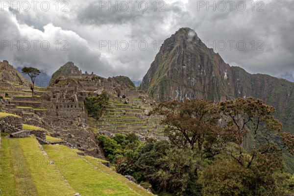 Terraced ruins of Machu Picchu surrounded by mountains and thick fog, The ruins of the Inca city of Machu Picchu in Peru
