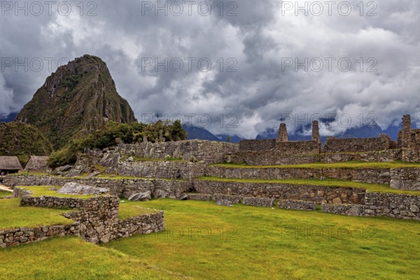Ancient ruins against a dramatic sky with dark clouds and green areas, The ruins of the Inca city of Machu Picchu in Peru