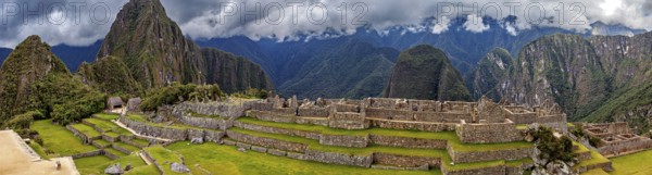 Wide view of Machu Picchu with stone terraces and clouds in the sky, The ruins of the Inca city of Machu Picchu in Peru