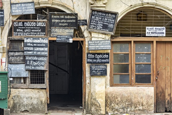 Old façade of a building with numerous colorful signs and wooden windows in colonial style, door with signs in Kandy Sri Lanka
