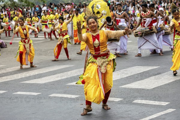 Woman in glowing traditional costume dances joyfully at a cultural parade, The Perahera Parade in Kandy Sri Lanka