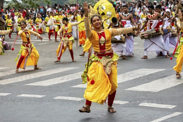 Dancers in colorful, traditional Indian costumes during a lively parade at a crossroads, The Perahera Parade in Kandy Sri Lanka