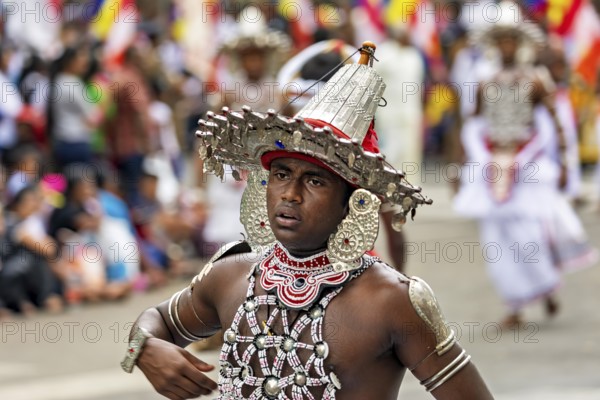 Close-up of a man wearing an elaborate, traditional headdress at a parade, The Perahera Parade in Kandy Sri Lanka
