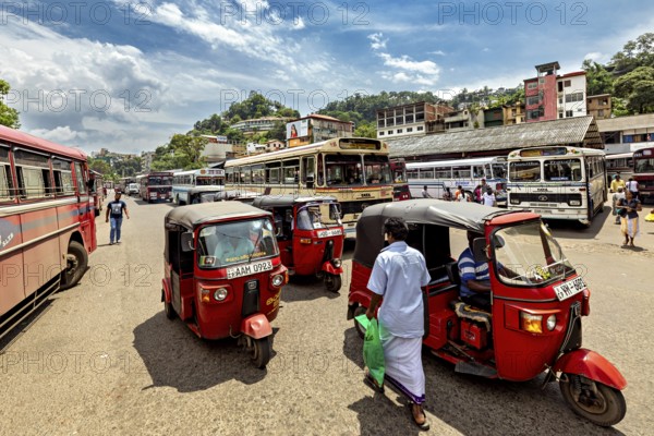 Bustling street scene with tuk-tuks and buses in an Asian city under blue skies, the bus station with tuk tuk in the city center of Kandy Sri Lanka