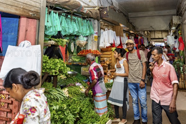 Customers and sellers in a lively vegetable stand at a market, dealers in the market halls of Kandy Sri Lanka