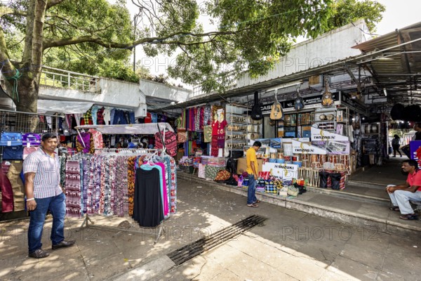 Market under trees, stalls selling clothes, relaxed market atmosphere, dealers in the market halls of Kandy Sri Lanka