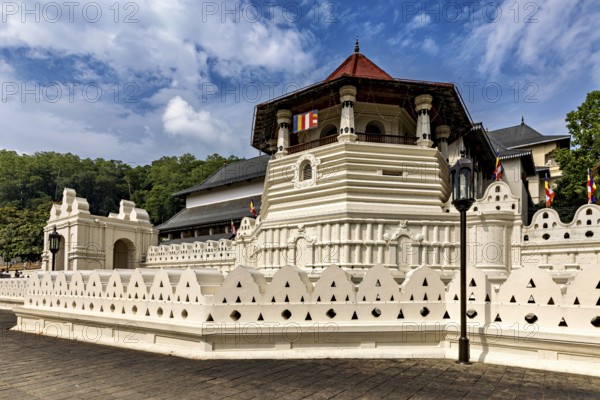 Historic red-roofed building surrounded by lush nature and peaceful atmosphere, The Temple of the Tooth in Kandy Sri Lanka