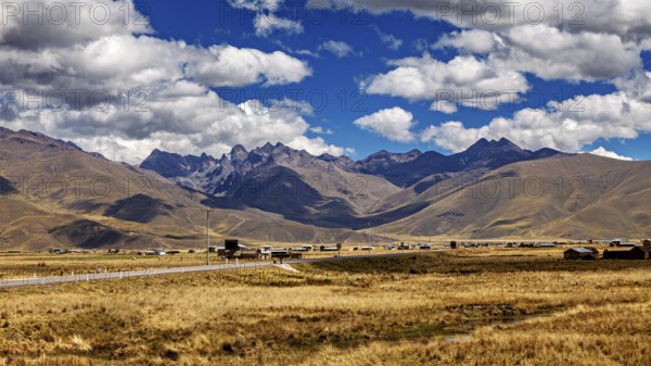 Wide landscape with a road between rolling mountains under a blue sky with clouds, The landscape in the highlands of Peru