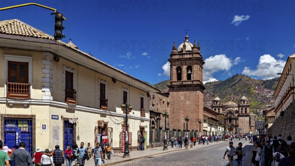 Historic city scene with colonial architecture and busy street life under blue skies, The churches of Cusco in Peru