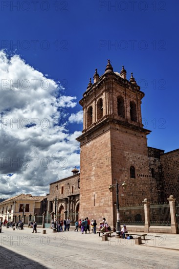 Distinctive bell tower and wall on a busy street under blue sky with clouds, The churches of Cusco in Peru