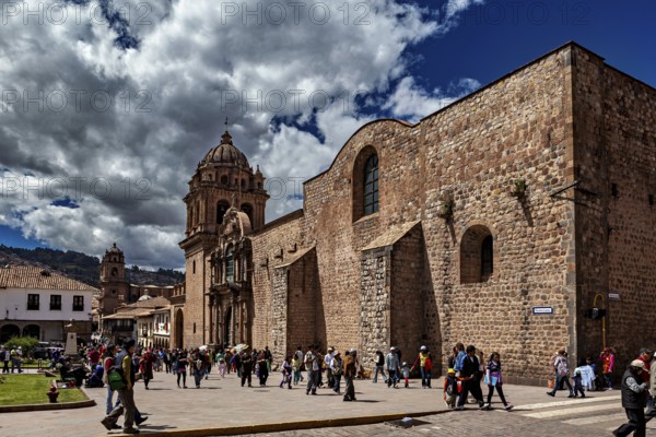 Classic church structure with a passing crowd against a dramatic cloudy sky, The churches of Cusco in Peru