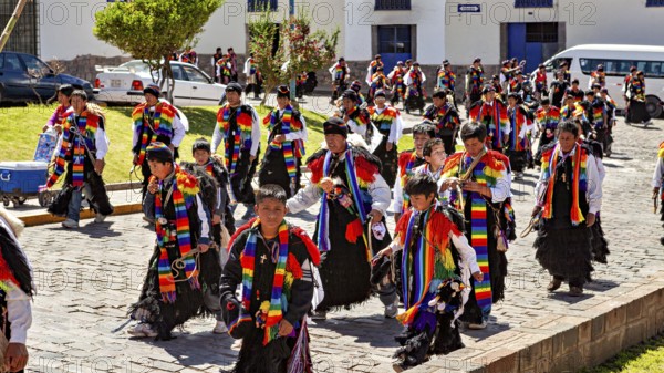Children and adults in traditional garments move in a colorful procession on the street, Traditional procession of festival groups in Cusco in Peru