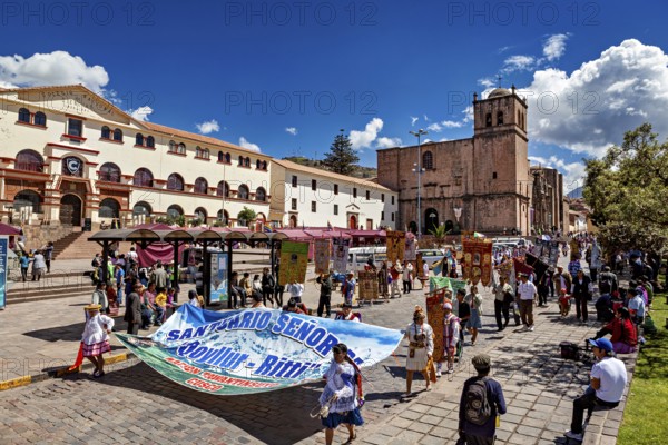 Bustling square with people and a church in the background, traditional parade of festival groups in Cusco in Peru