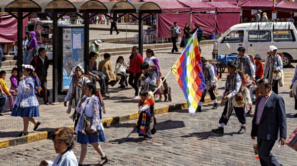 People wearing traditional clothes with colorful flags on a street, traditional parade of festival groups in Cusco in Peru