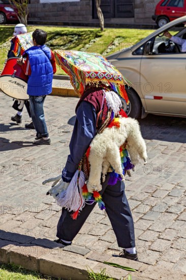 Person with traditional robe and colorful headdress on a street, traditional parade of festival groups in Cusco in Peru