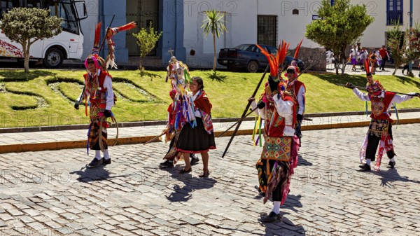 Dancers in colorful costumes with feather headdress perform a traditional performance on the street, traditional parade of festival groups in Cusco in Peru