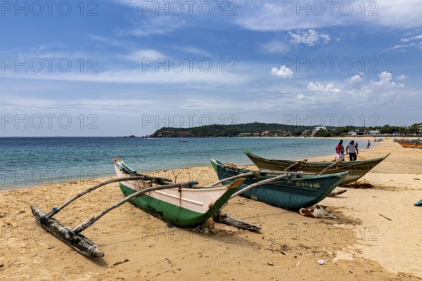 Beach backdrop with green fishing boats in the sand, clear turquoise water and blue sky, traditional boats on Trincomalee beach in Sri Lanka
