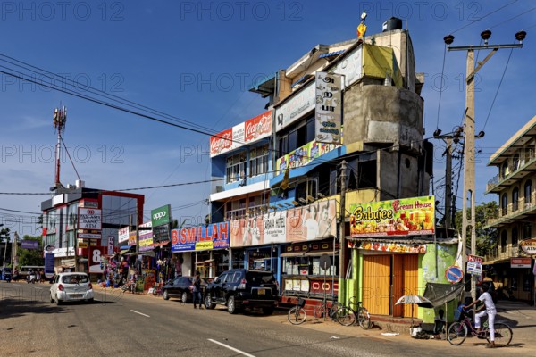 Busy urban street with shops and advertising signs under clear skies, the city of Trincomalee in Sri Lanka