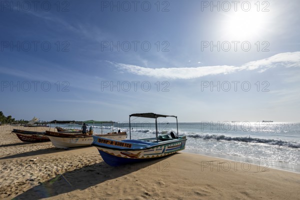 Boats are moored on a sunny beach with soft waves and clear skies, a peaceful atmosphere, Trincomalee beach in Sri Lanka