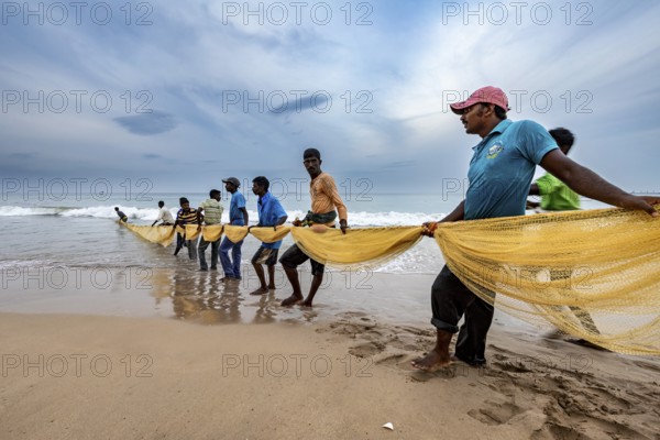 Fishing community draws a long net from the sea, focus on teamwork, traditional fishermen on Trincomalee beach in Sri Lanka