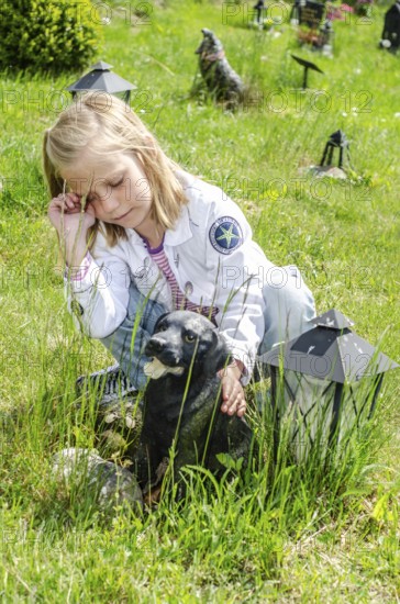 Grieving blonde 7-year-old girl at her dog's grave at pet cemetery in Ystad, Skåne County, Sweden, Scandinavia