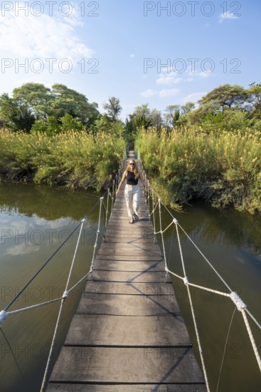 Toruist on the Kavango River, suspension bridge at Camp Kwando, Zambezi region, Caprivi Strip, Namibia