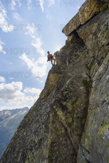 Female mountaineer on steep rock face on the secured via ferrata Krokodil-Bergsee am Bergseeschijen-Vorbau, Sonnenstern, Göscheneralp, Canton of Uri, Switzerland