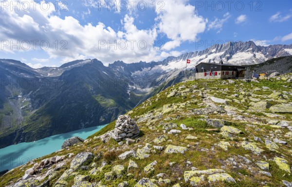 Mountain hut Bergseehütte with Swiss flag in picturesque mountain landscape, view of Damma Glacier and Dammastock, Göscheneralp, Canton of Uri, Switzerland
