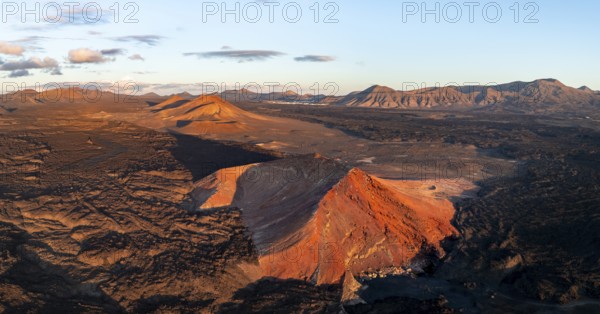 Picturesque volcanic landscape in evening light, red volcano Montaña Bermeja between lava fields, aerial view, Lanzarote, Canary Islands, Spain