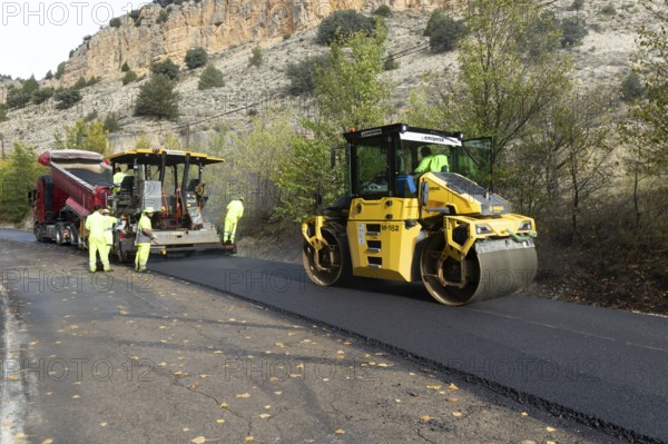 Asphalt road construction team of workers resurfacing tarmac in rural area, near Albarracin, Teruel province, Aragon, Spain