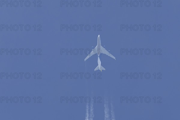 Boeing 747 jumbo jet cargo aircraft flying in a blue sky with contrails or vapour trails behind, England, United Kingdom