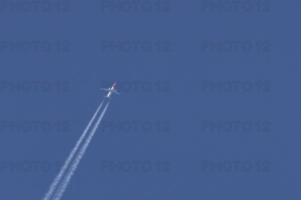 Boeing 737 jet passenger aircraft of Norwegian Air airlines flying in a blue sky with contrails or vapour trails behind, England, United Kingdom