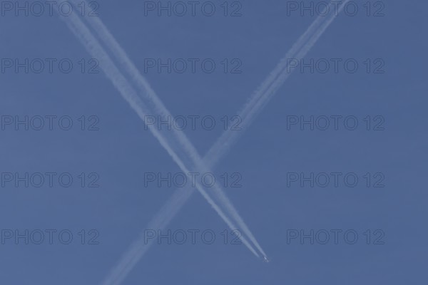 Aircraft contrails or vapour trails crossing in a blue sky, England, United Kingdom
