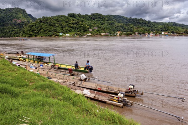 Wooden boats with motors on the banks of a river surrounded by hills, longboat on a river near Rurrenabaque in the Amazon jungle in Bolivia