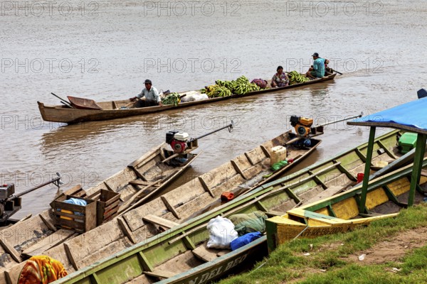 People in wooden boats with bananas and engines on the river, longboat on a river near Rurrenabaque in the Amazon jungle in Bolivia