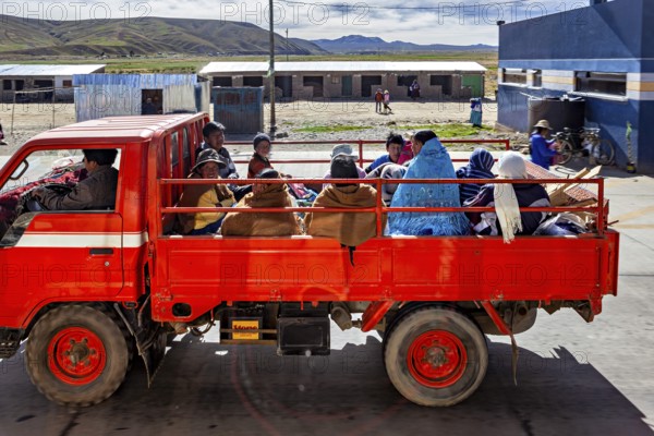 A red truck transports several people through a rural area in a quiet atmosphere, Road traffic in the city of La Paz in Bolivia