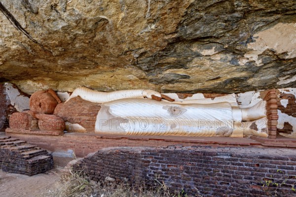 Reclining Buddha embedded in a rock wall, made of sandstone, peaceful and meditative atmosphere, The sleeping Buddha on Pidurangala rock near Sigiriya in Sri Lanka
