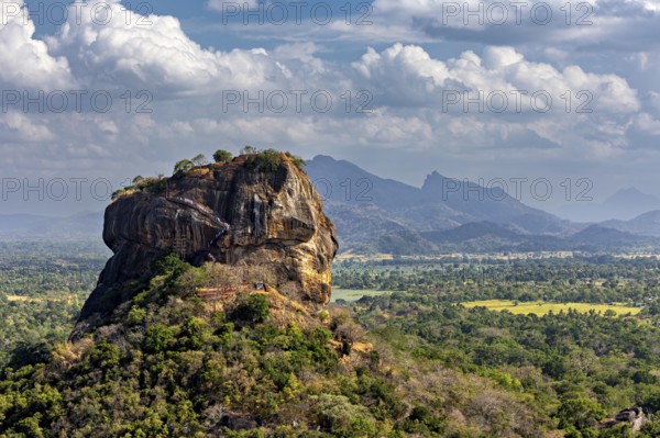 Panorama of an imposing rock formation with mountainous landscape and clouds in the background, The Lion Rock near Sigiriya in Sri Lanka
