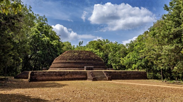 An old brick stupa surrounded by thick greenery and a cloudy sky, the temples, dagobas, and pagodas at Lion Rock near Sigiriya in Sri Lanka