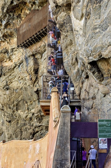 People climb a steep, rock-like structure, tourist attraction with climbing elements, tourists at the temples and rocks of Lion Rock near Sigiriya in Sri Lanka