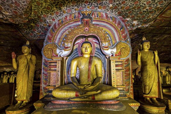 Central Buddha in a richly decorated frame within a cave decorated with ornaments, The cave temples of Dambulla in Sri Lanka