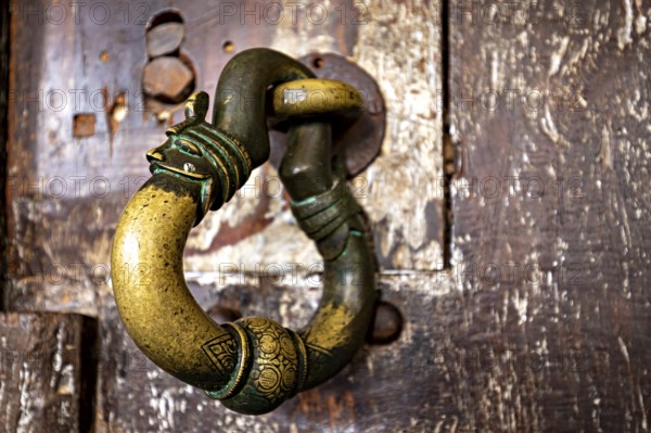 Antique brass door knocker on weathered wood, conveys a nostalgic and historic charm, door handle at the cave temple of Dambulla in Sri Lanka