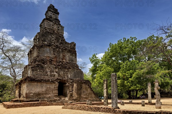 Historic ruins with a tall stone tower and trees in an open area, The temples of Polonnaruwa in Sri Lanka