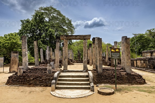 Entrance with ancient columns and sandy soil under a partly cloudy sky, The temples of Polonnaruwa in Sri Lanka